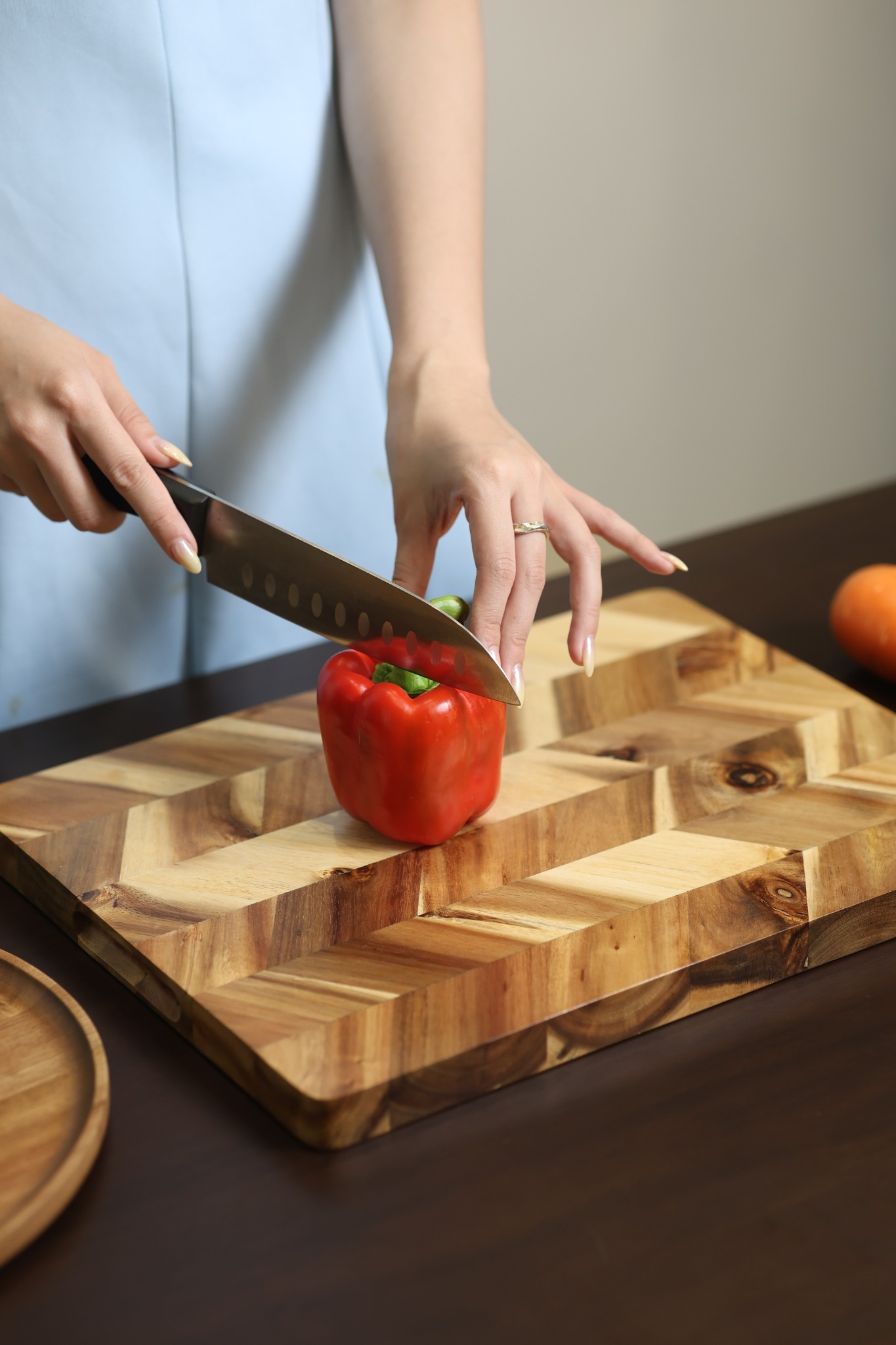Acacia end-grain cutting board used for food preparation with a red pepper